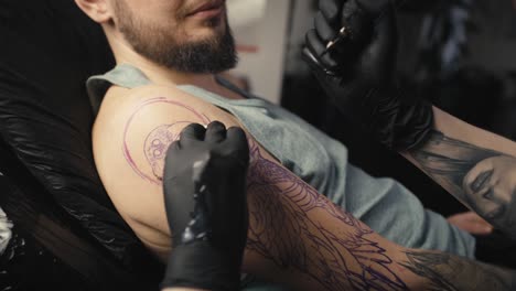 un primer plano de una artista tatuando los brazos de su cliente.