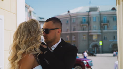 confident man touches cheek of beloved bride on street