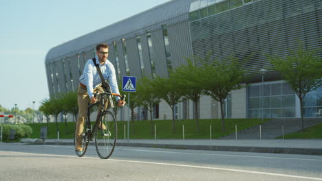 handsome man wearing glasses and riding a bicycle, then stopping and looking at his watch