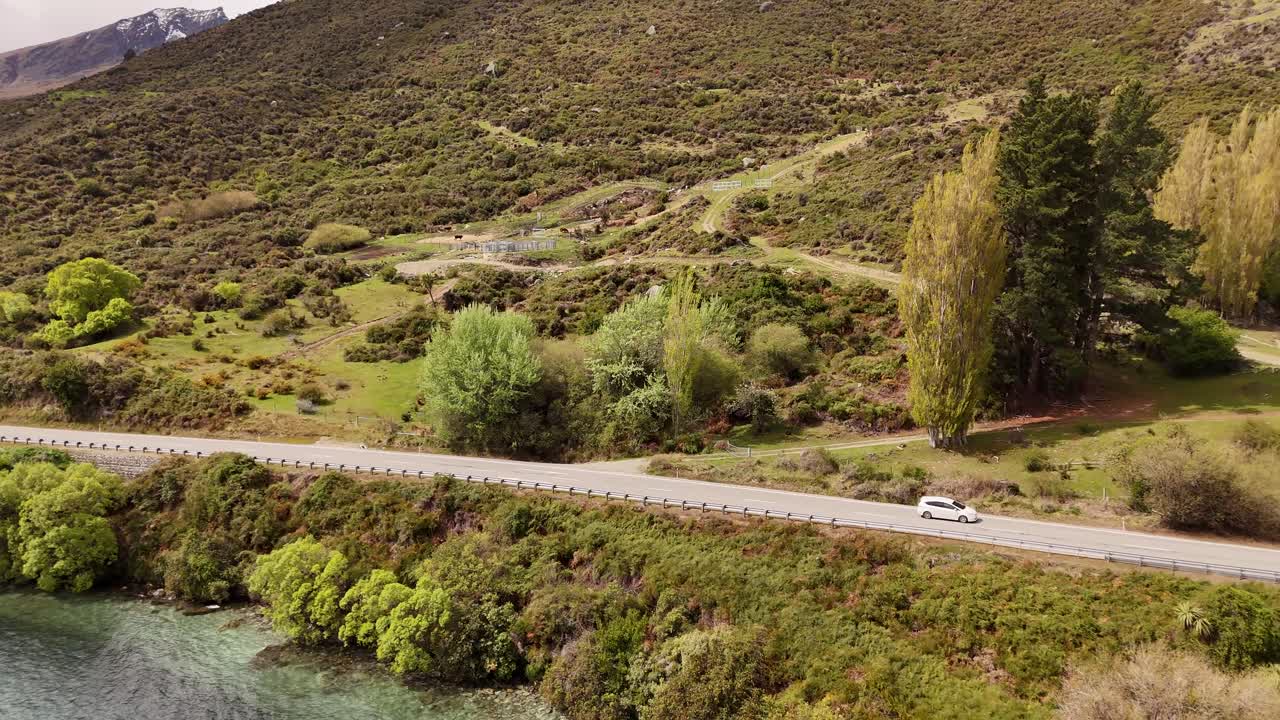 Auto ajaa tietä pitkin Wakatipu-järven ja Eteläsaaren vuoriston vieressä Uuden-Seelannin Otagon alueella.