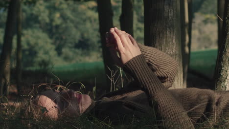 young women lie on the grass relaxing and playing with leaves