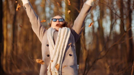 positive happy woman throwing leaves in autumn in park