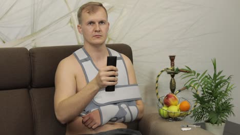 a man with a broken arm in a sling sitting on a couch