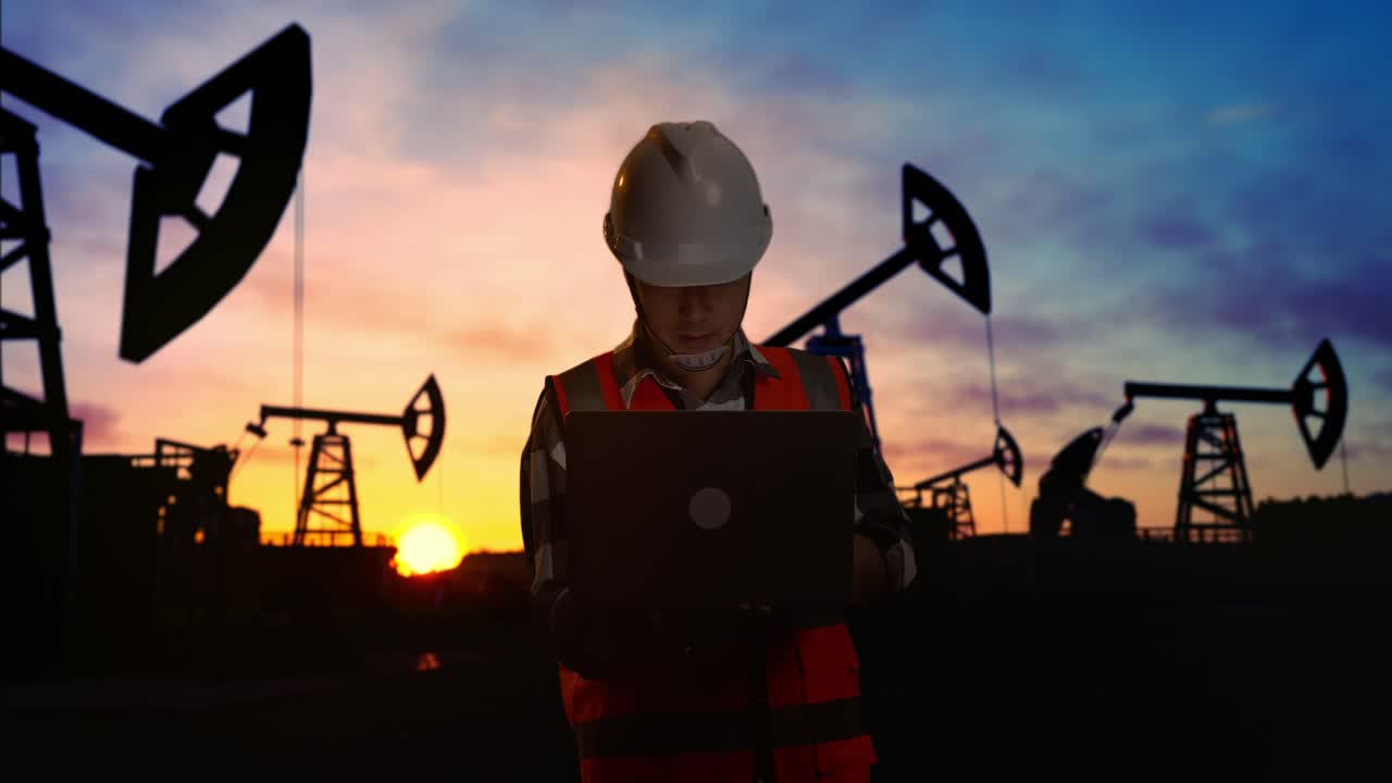 ingeniero de plataforma petrolera trabajando en una computadora portátil al atardecer