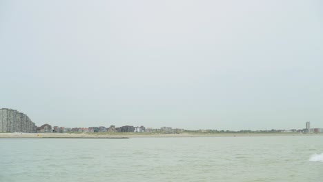 barco de pesca comercial que pasa por el mar del norte con en el fondo la costa belga de nieuwpoort - bélgica