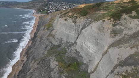 slow aerial approach of the massive cliff sides of the charmouth beach hills