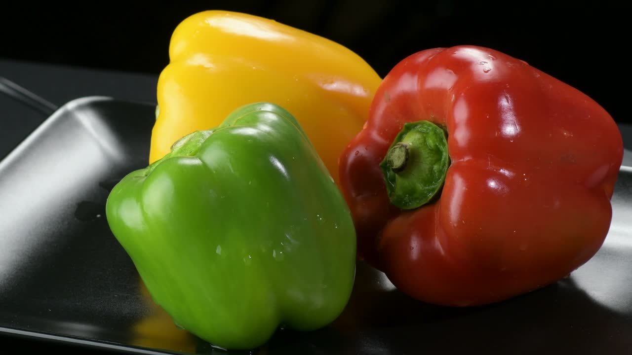 신선한 고추 노란색, 빨간색 및 녹색 채소 검은색 트레이에 회전