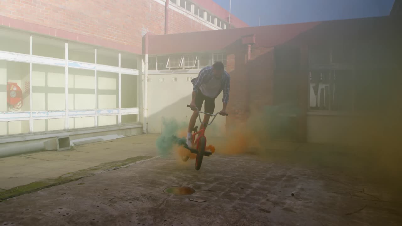 jinete de bmx en un almacén vacío usando una granada de humo