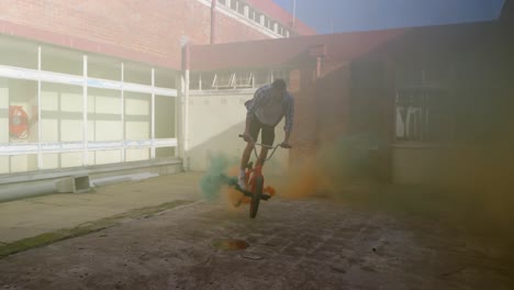 bmx rider in an empty warehouse using smoke grenade