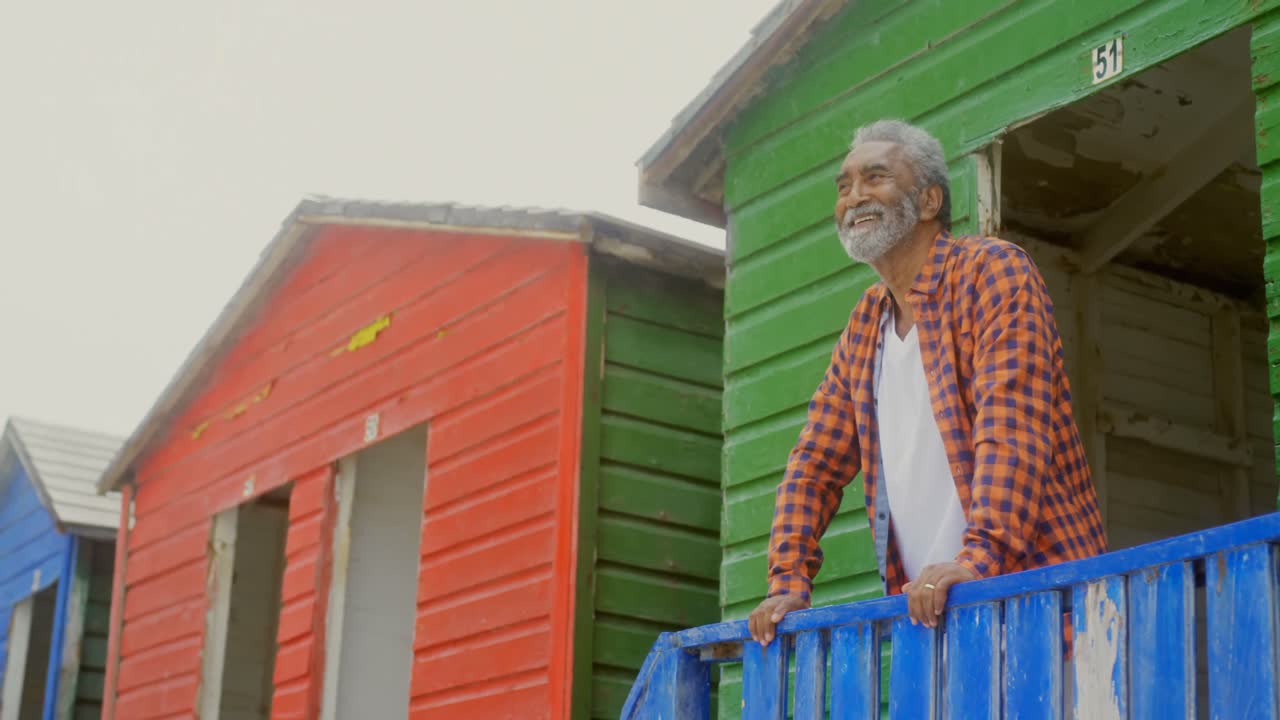 Low angle view of happy active senior African American man standing at beach hut on a sunny day 4k