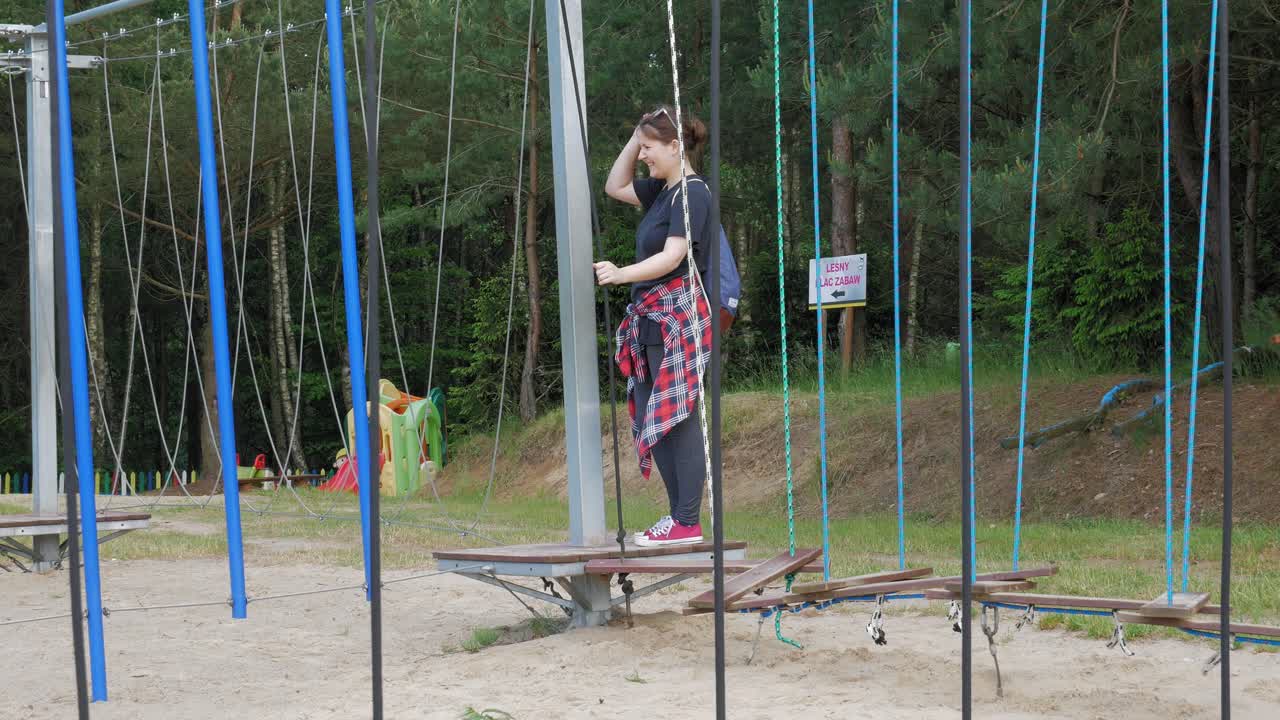 una mujer turista divirtiéndose en la plataforma del puente colgante en el parque kazubski gigantow en polonia - ancho