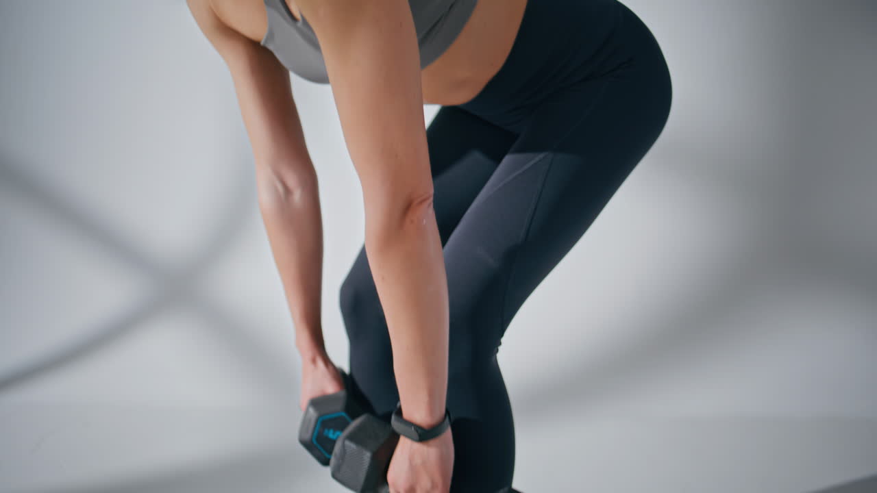 Athletic woman training dumbbells in gym closeup. Fitness girl lifting weights