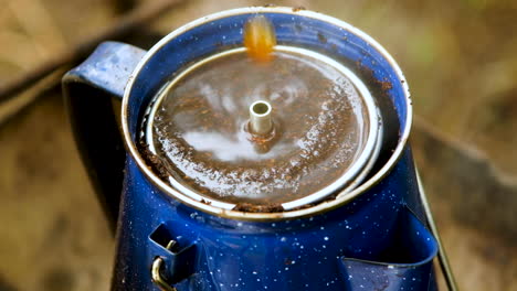 Close-up-of-enamel-percolator-coffee-set-on-fire-spewing-out-hot-black-coffee