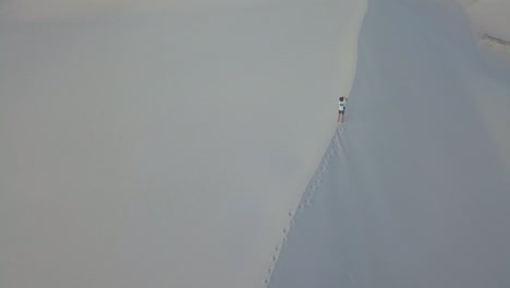 dramatic aerial of man hiking on sand dunes in south africa