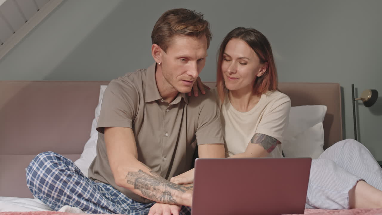 pareja usando la computadora portátil en la cama
