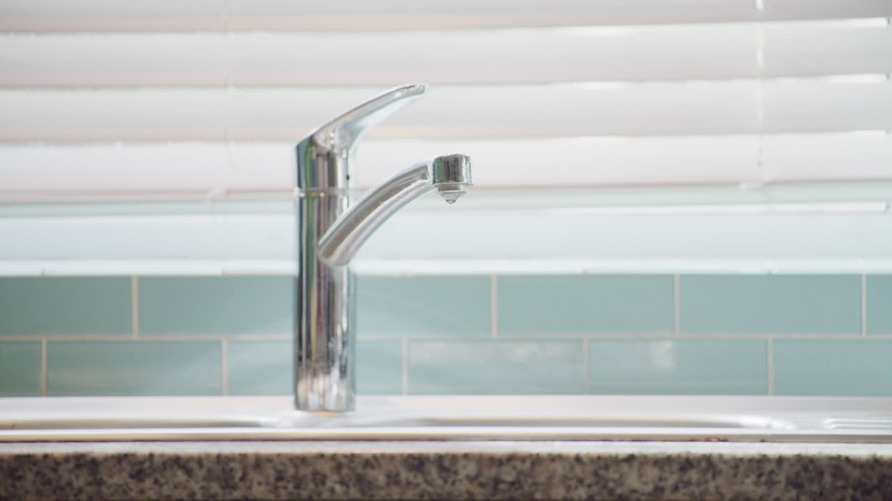 acqua che gocciola da un rubinetto a casa