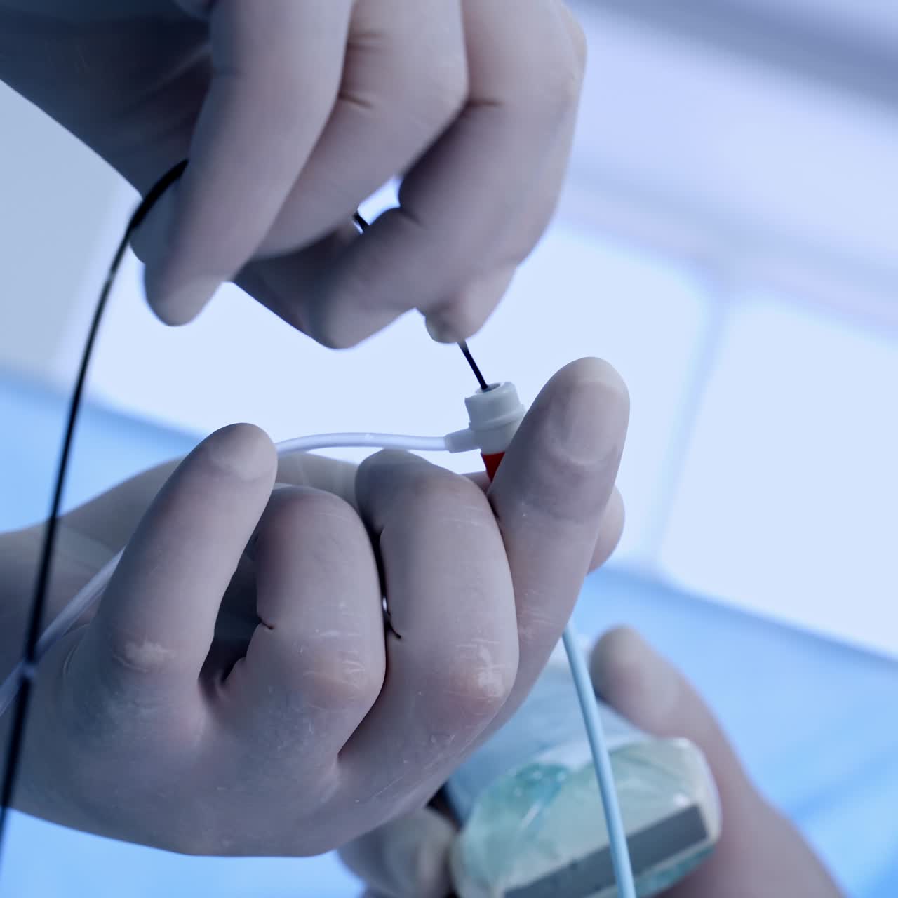 Surgeon's hands in latex gloves holding instruments during operation. Doctor uses equipment for vascular surgery. Close up