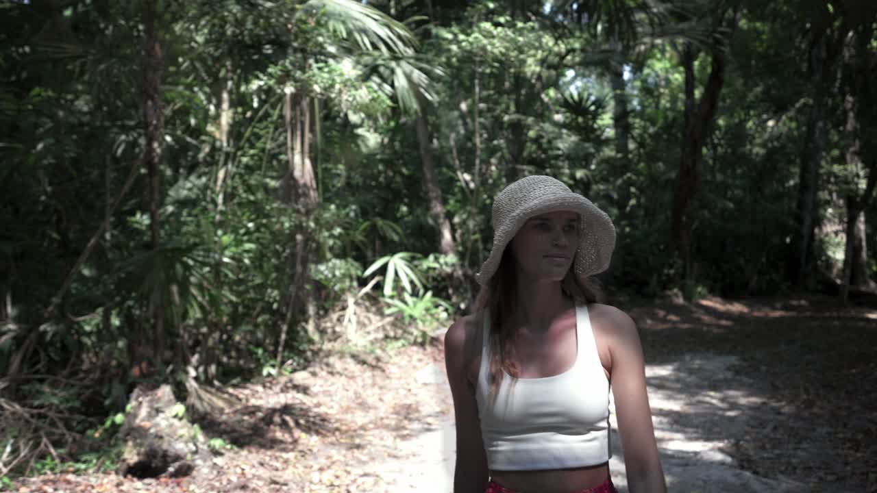 una mujer turista caminando felizmente por un largo camino de la selva dentro del parque nacional de tikal, guatemala