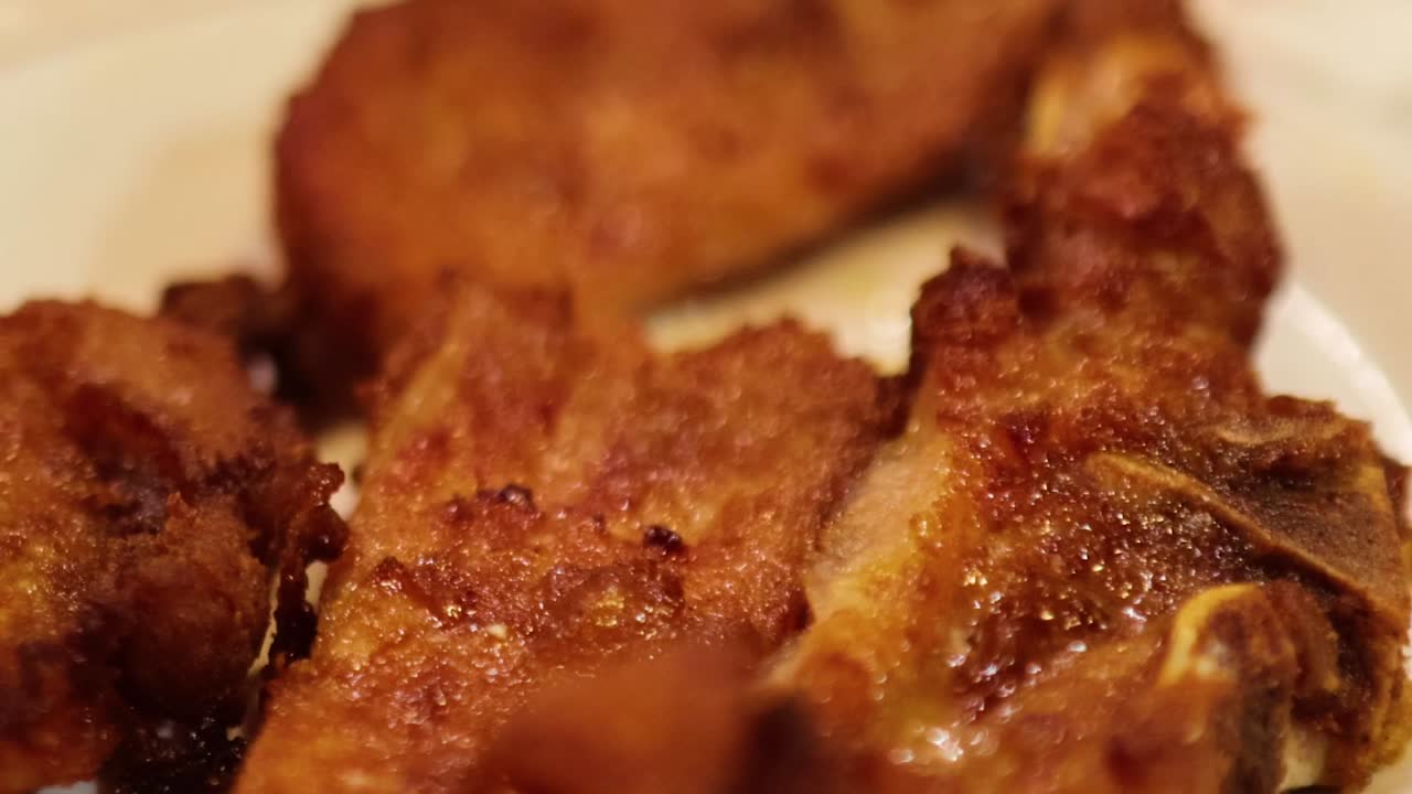 Zoomed-in view of crispy, golden-brown fried pork pieces arranged on a decorative plate.