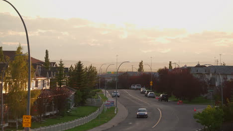 colorful sunset at golden hour in the city with houses with a road leading into the distance with cars driving.