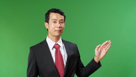 Asian Businessman Pointing On Something And Talking On A Green Screen, Chroma Key