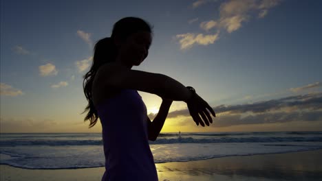 toned ethnic woman running and resting on beach