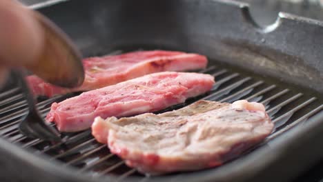 hand turns lamb chops cooking in a grill pan