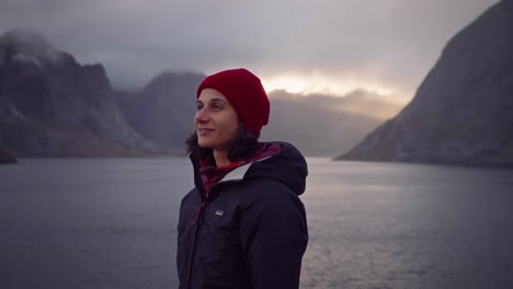 orbit shot around an ecstatic young woman smiling while admiring the sunset in hamnøy, lofoten islands, norway