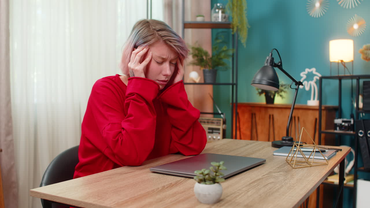 Woman tiredly closing laptop suffering headache after long exhausting stressful remote online work