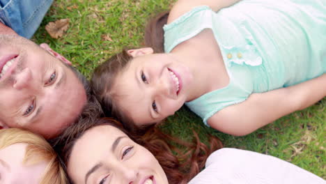 happy family lying on grass and looking at camera