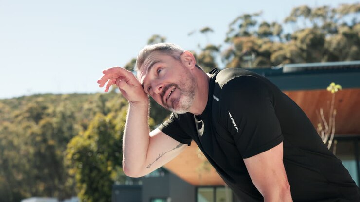 Tired Man Wiping Sweat from Forehead After Outdoor Workout