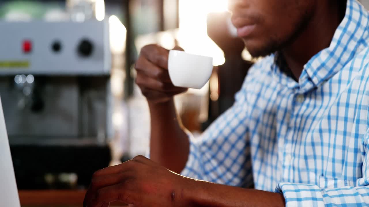 hombre usando una computadora portátil mientras tiene una taza de café