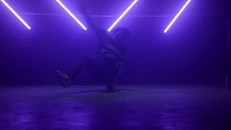 hiphop performer making tricks on stage. active man freestyling in ultraviolet.