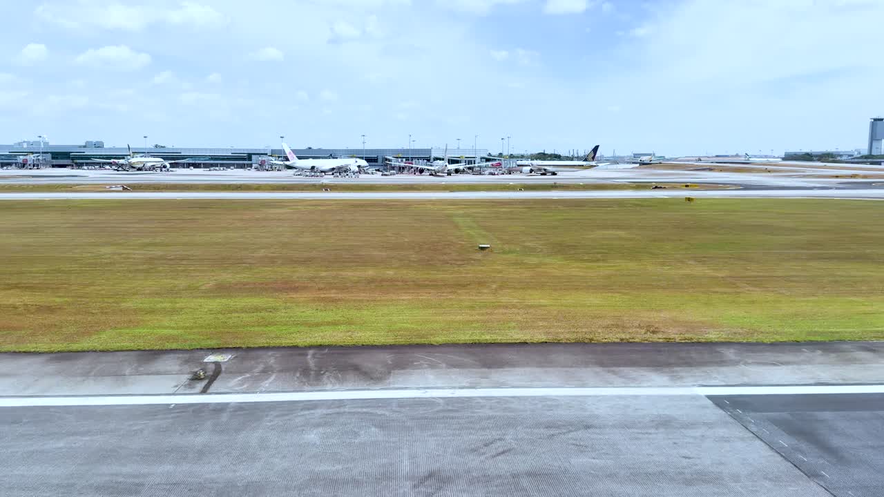 Rekaman sudut pandang dari jendela pesawat yang bergerak melewati rumput dan infrastruktur bandara.