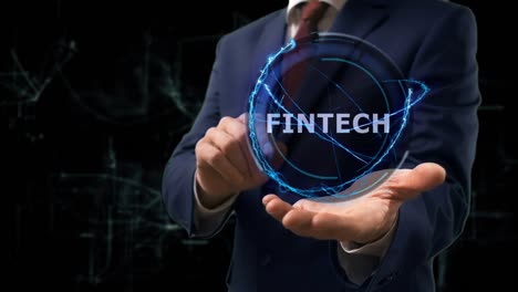 un hombre de negocios muestra un holograma conceptual de fintech en su mano.