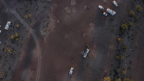 Vista-Aérea-De-Arriba-Hacia-Abajo-De-Vehículos-Recreativos-Estacionados-En-Un-Desierto-De-Arizona,-Inclinando-El-Sol