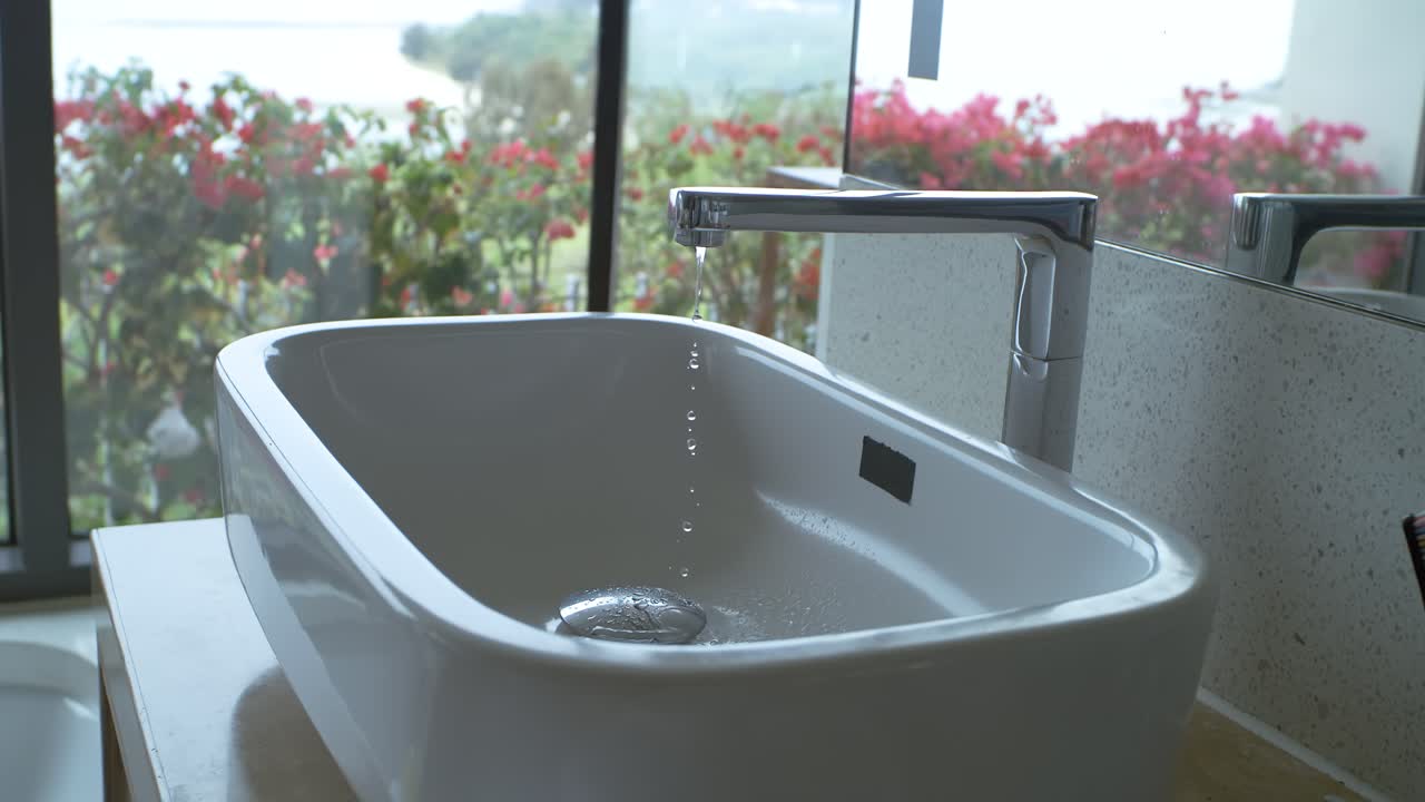 Drops of water slowly drip from the faucet in the bathroom. Dripping faucet Shot on super slow motion camera 1000 fps.