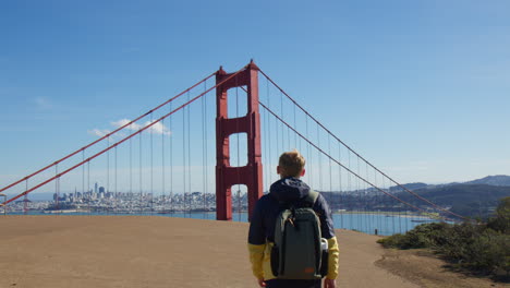 man walking at viewpoint with view of golden gate bridge tower in san francisco, california