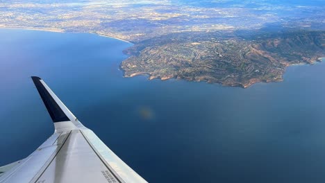 looking out a commercial airplane window at the los angeles coastline