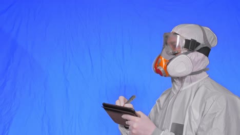 scientist virologist in respirator makes write in an tablet computer with stylus. man wearing protective medical mask. chroma key blue.