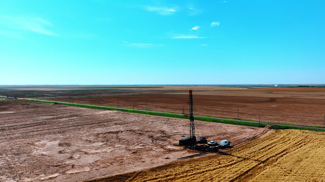 A truck with portable drilling tower at the back. Cars and machines for natural resources boring. Aerial perspective.