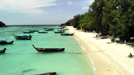 Rückwärtsflug-über-Boote,-Die-An-Einem-Strand-Mit-Klarem-Wasser-Vor-Anker-Liegen