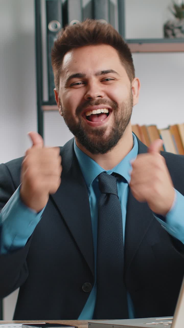Un uomo d'affari felice che guarda con approvazione la telecamera mostrando i pollici in alto come un segno positivo di buone notizie