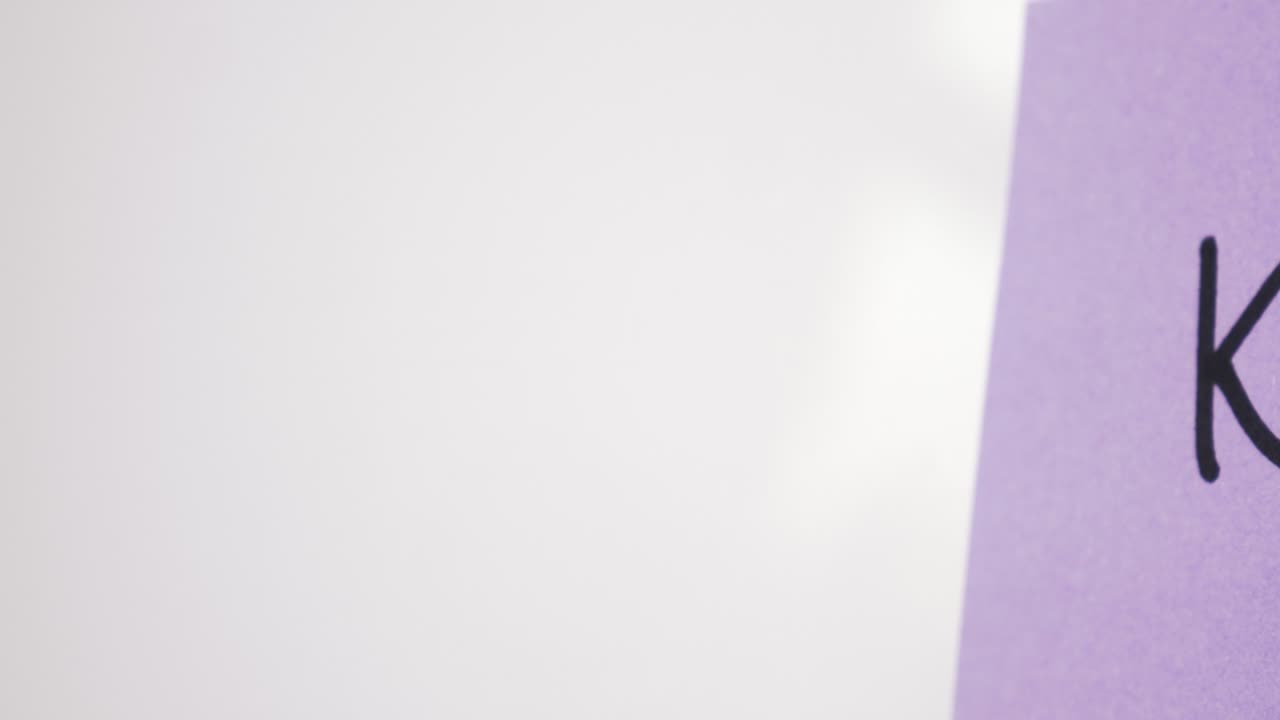 Pan reveal of KPI text on purple note held by magnet on whiteboard with selective focus