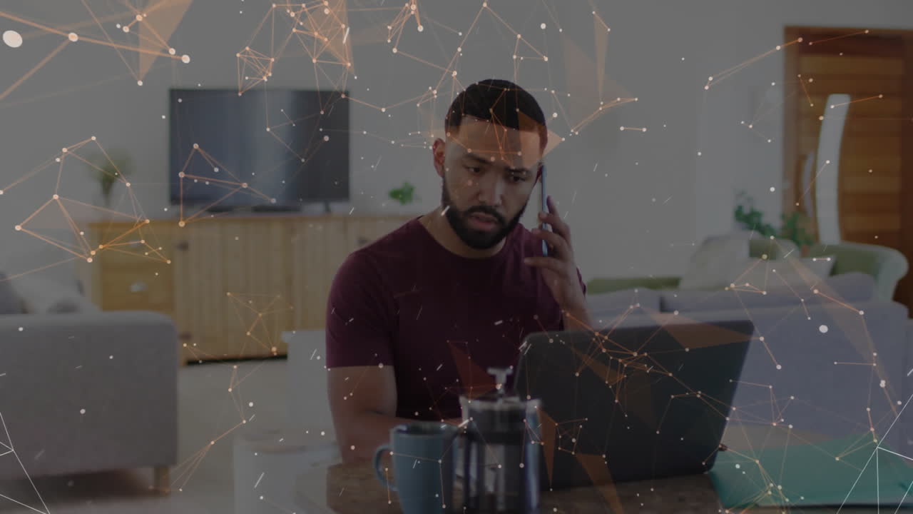 Man holding smartphone and using laptop in technology workspace, showing connected network overlay