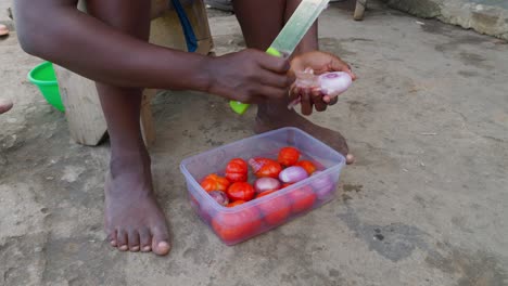 ghanaian black woman fighting with knife onion and vegetables to prepare bunku national dish of ghana