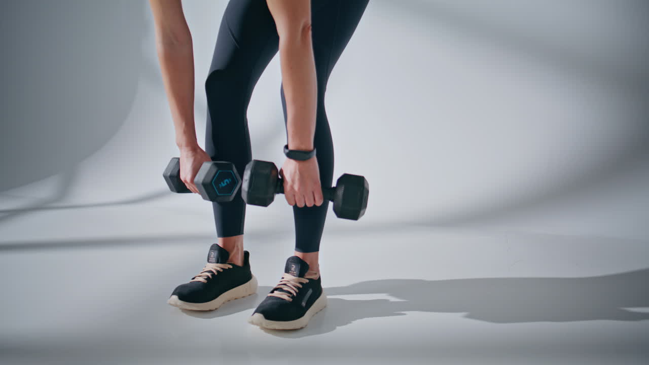 Unknown sportswoman dumbbells workout at studio closeup. Lady training hands