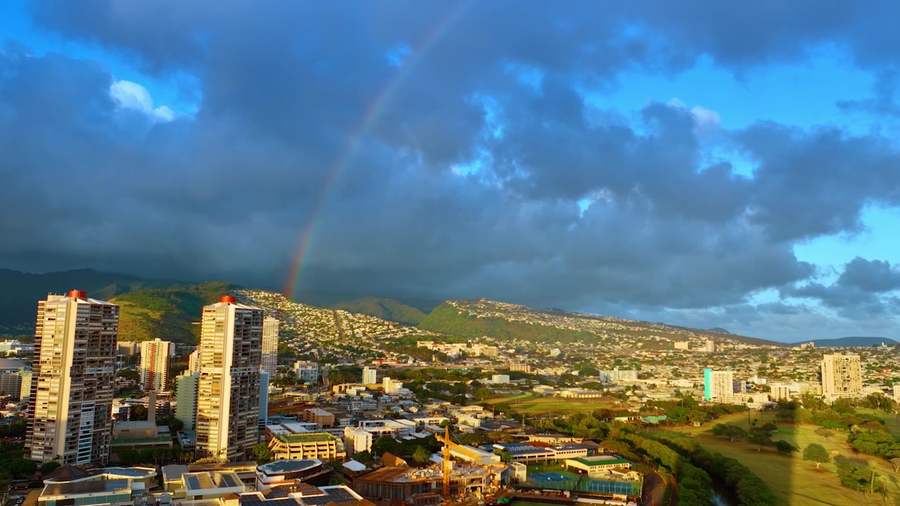 Enormi nuvole raccolte sopra il paesaggio di Honolulu al tramonto. Un bellissimo arcobaleno luminoso si alza sopra la città. Hawaii, USA