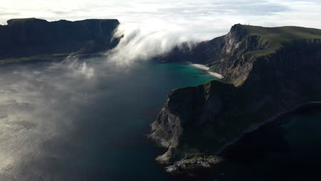 Wide-drone-footage-of-clouds-pouring-over-the-mountain-ridge