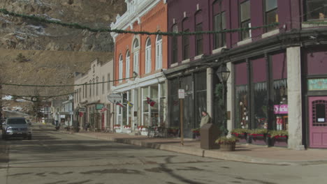 View-from-left-to-right-of-houses-with-shops-along-the-mainstreet-in-western-state-of-Utah-with-snow-covered-high-mountains-in-background-in-United-States